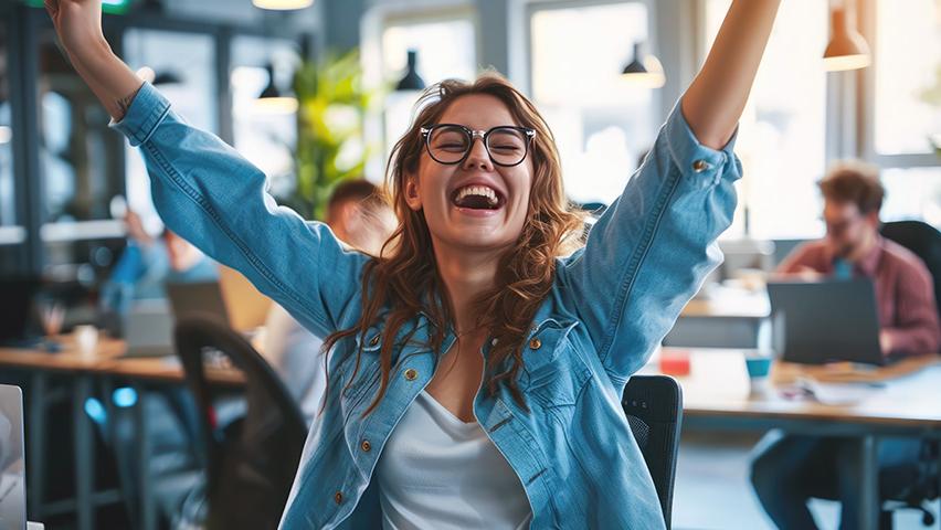 Young woman very happy with arms stretched above sitting in office